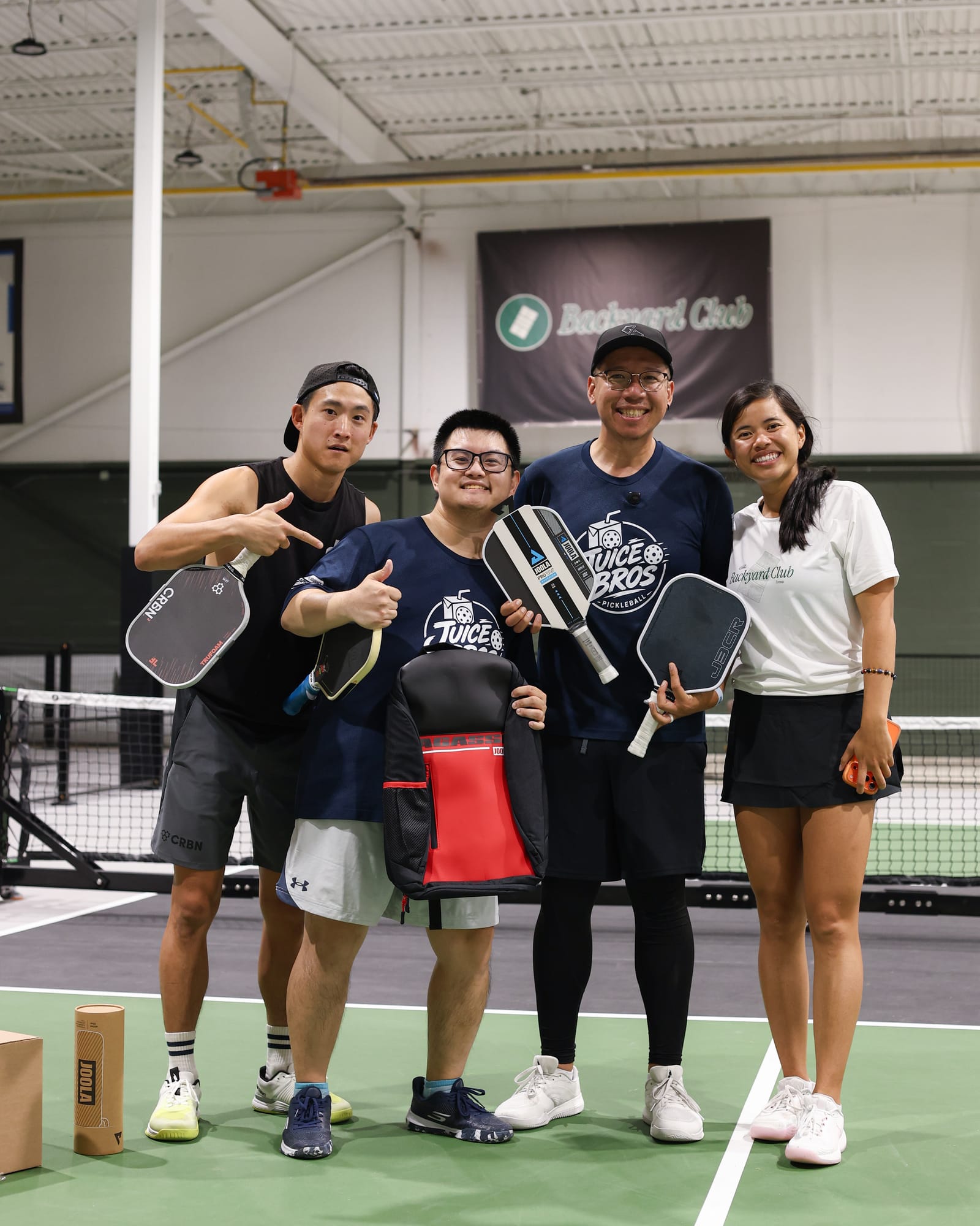 Daven and Adrian with two other players at The Backyard Club, paddles in hand, grinning at the camera