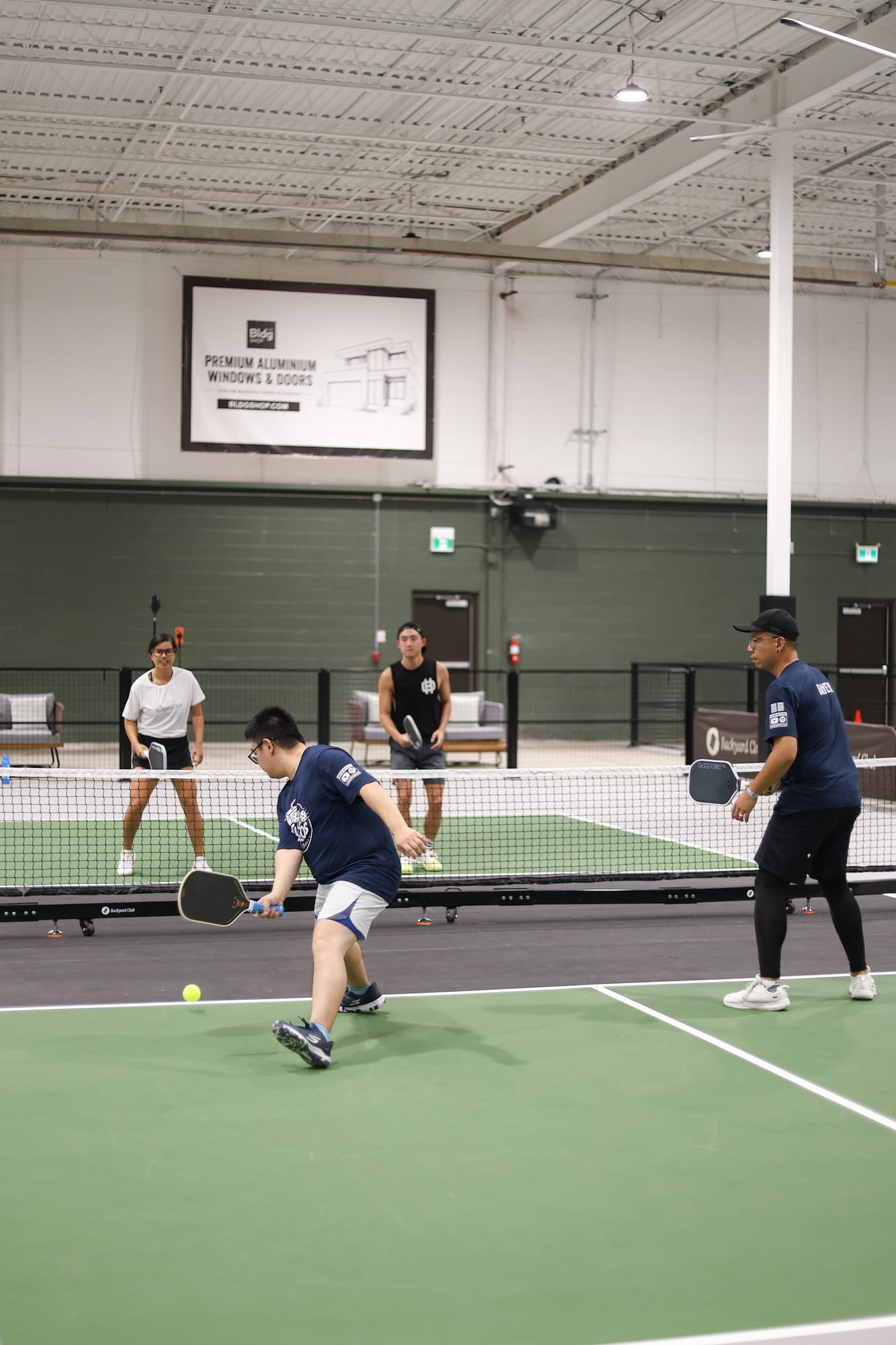 Adrian lunging low for a ball near the kitchen line, Daven beside him at the net